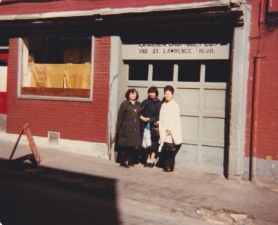Trois femmes prennent la pose devant la porte de garage d’une entreprise