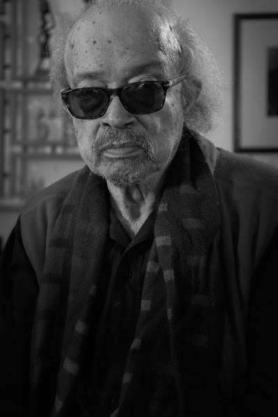 Photo noir et blanc en plan taille d’un homme noir portant des lunettes fumées.