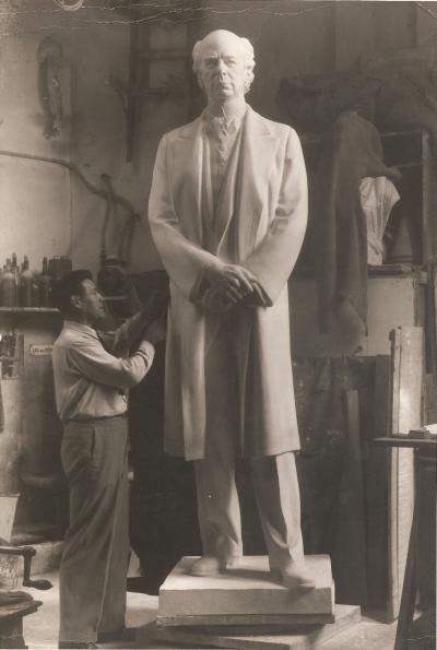 Photographie d'Émile Brunet travaillant sur une grande sculpture dans un atelier.