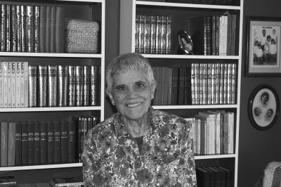 Photo en noir et blanc montrant une femme en plan rapproché avec des bibliothèques en arrière-plan.