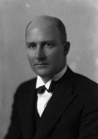 Photographie en noir et blanc d’un homme en plan rapproché taille portant un complet.