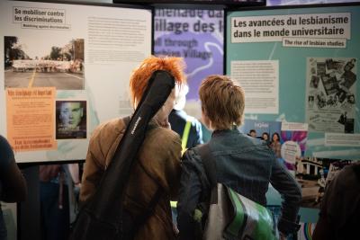 Deux personnes regardent des modules d’exposition dans un espace public.