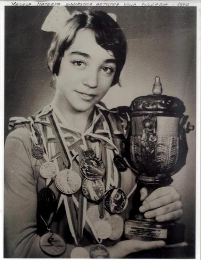 Photo noir et blanc d’une athlète de 16 ans en format taille avec plusieurs médailles autour du cou et un trophée qu’elle tient dans ses mains.