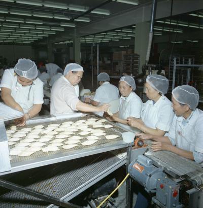 Photo couleur montrant des travailleurs et des travailleuses dans une usine de fabrication d’aliments chinois. 