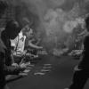 Photo noir et blanc montrant des hommes jouant aux cartes dans une salle enfumée.