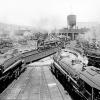 Photographie en noir et blanc de la rotonde Turcot. En arrière-plan, la falaise Turcot et l’immeuble du 780, rue Saint-Rémi derrière la tour d’eau de la gare de triage Turcot. 