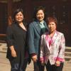 Photo couleur plein pied de trois femmes souriantes posant debout sur la place Sun-Yat-Sen dans le Quartier chinois. 