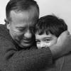 Photo en noir et blanc montrant un grand-père enlaçant son petit-fils en plan rapproché.
