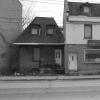 Photo noir et blanc montrant une petite maison et un dépanneur délabrés