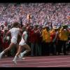 Photographie des deux relayeurs, vêtus de blanc, qui courent sur la piste en tenant la torche olympique.