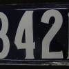 Photographie d’une plaque d’adresse rectangulaire avec les chiffres 8421 écrits en blanc sur fond bleu. 