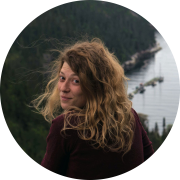 Photo couleur d’une jeune femme souriante avec un paysage de montagne et d’un cours d’eau en arrière-plan