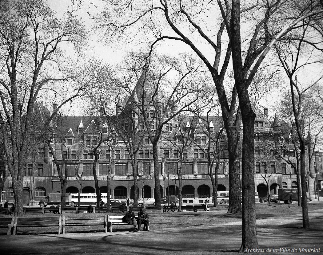 Photographie du square Viger et de l'édifice Jacques-Viger à travers les arbres.