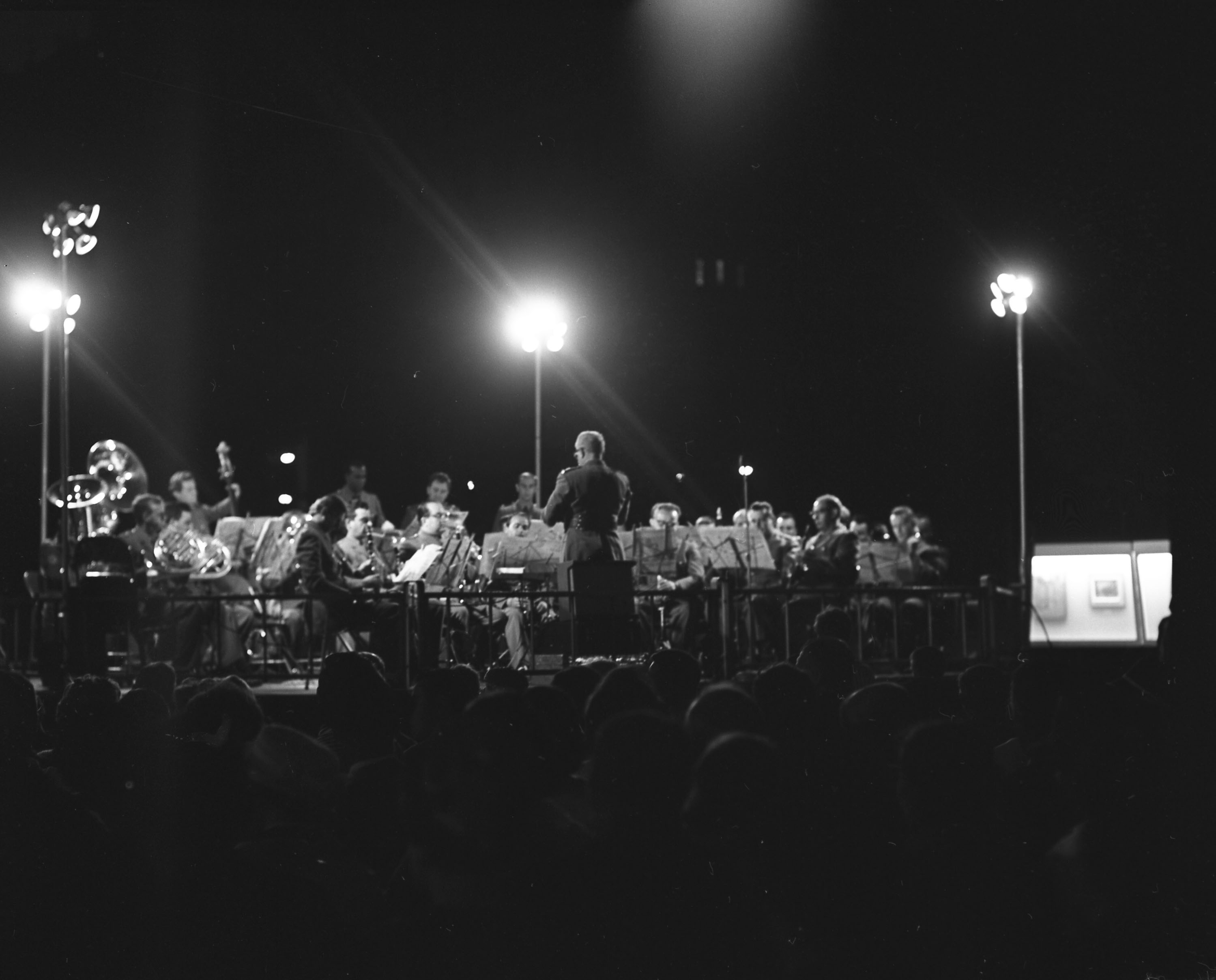 Photo noir et blanc d’un ensemble d’harmonie jouant dans un square le soir.