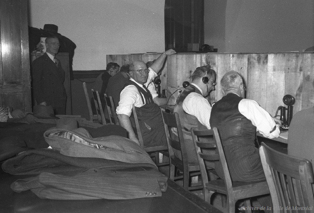 Photographie des employés préposés à la réception des appels des résultats du vote dans une salle aménagée pour les élections. 