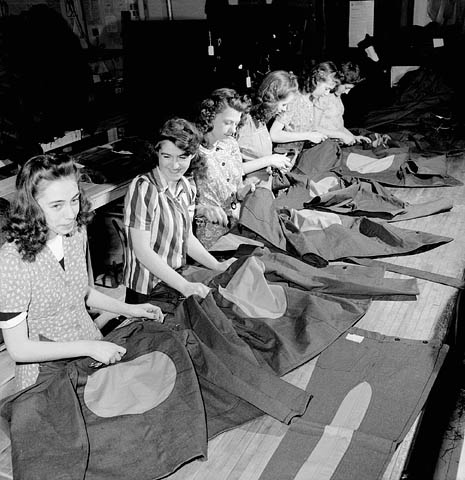 Des ouvrières de l'usine Standard Overalls Company cousent de grands cercles rouges sur les vestons et des bandes rouges sur les pantalons des prisonniers de camp d'internement canadien.
