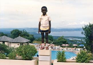 Un enfant juché sur un bloc avec une piscine et un plan d'eau en arrière-plan