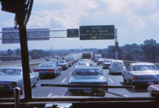 Voitures en file dans les trois voies de l'autoroute 15 sud. On voit le panneau indiquant la sortie vers Verdun et la jonction avec l'autoroute 10.