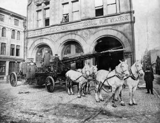 Pompiers et chevaux devant la caserne, affichant « CASERNE CENTRALE DE POMPIERS - CENTRAL FIRE STATION »