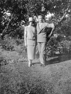Photo en noir et blanc d’un couple prenant la pose sur une pelouse avec des arbres derrière eux