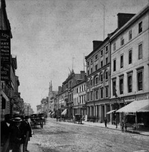 Photographie d'une rue avec de hautes façades et de calèches.