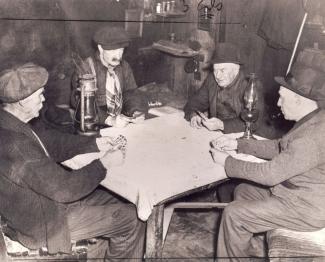 Quatre hommes âgés assis autour d’une table jouent aux cartes