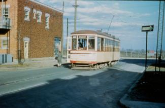 Photographie couleur d'un tramway électrique et d'un bâtiment. La devanture du wagon affiche « ROSEMONT ».