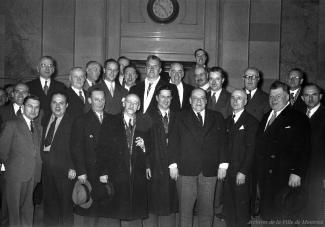 Photographie d’un groupe d'employés et de conseillers municipaux dans le hall d’honneur.