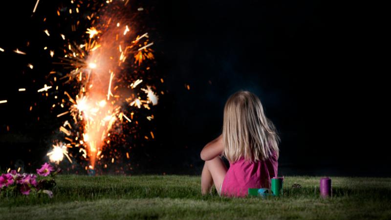Une fillette regarde des feux d&#039;artifices, dans un contexte domestique.