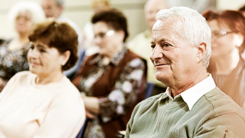 Des personnes âgées assistent à une conférence.