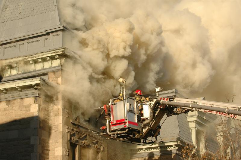 Des pompiers travaillent à éteindre un incendie au haut d'un immeuble.