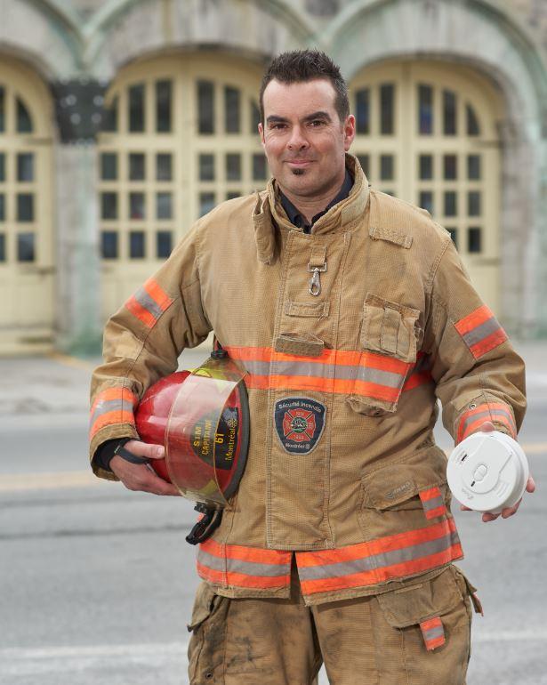 Capitaine de pompier avec un avertisseur de fumée dans ses mains.