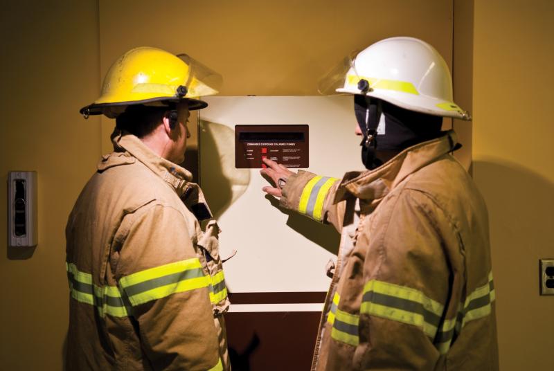 Deux pompiers du SIM se servant du panneau d'affichage d'alarmes et de pannes.