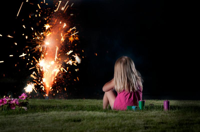 Une fillette regarde des feux d'artifices, dans un contexte domestique.