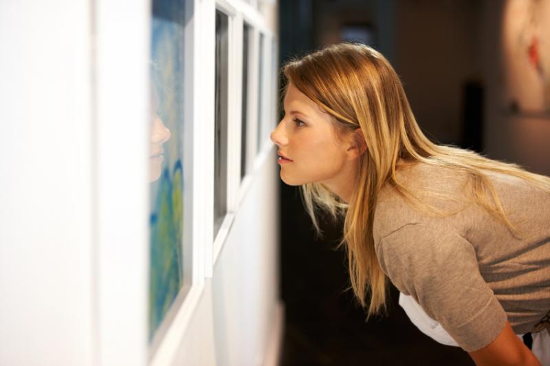 Une jeune femme contemple attentivement une œuvre d'art, lors d'une exposition.