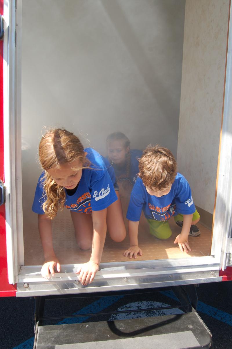 Des enfants s’exercent à évacuer le SIMulateur en présence de fumée non-toxique.