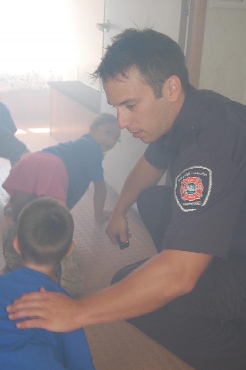 Encadrés par un pompier éducateur, des enfants s’exercent à évacuer le SIMulateur en présence de fumée non-toxique.