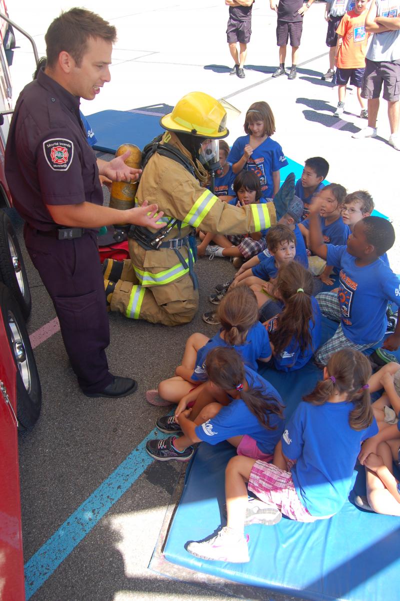 Deux pompiers éducateurs expliquent leur travail aux enfants.