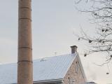 Une haute cheminée en brique s’élève derrière l’entrepôt. Photographie.
