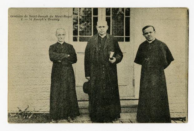 Trois membres de la congrégation de Sainte-Croix photographiés en pied devant une porte de l’Oratoire Saint-Joseph.