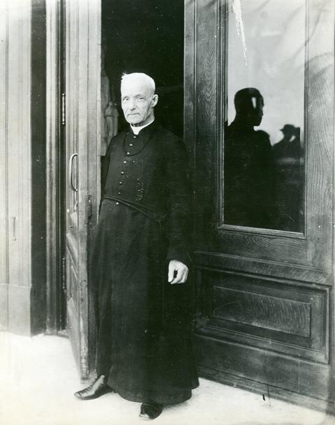 Le frère André debout à la porte de la crypte de l’Oratoire.