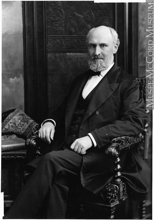 Portrait de William Macdonald, assis sur un fauteuil, jambes croisées.