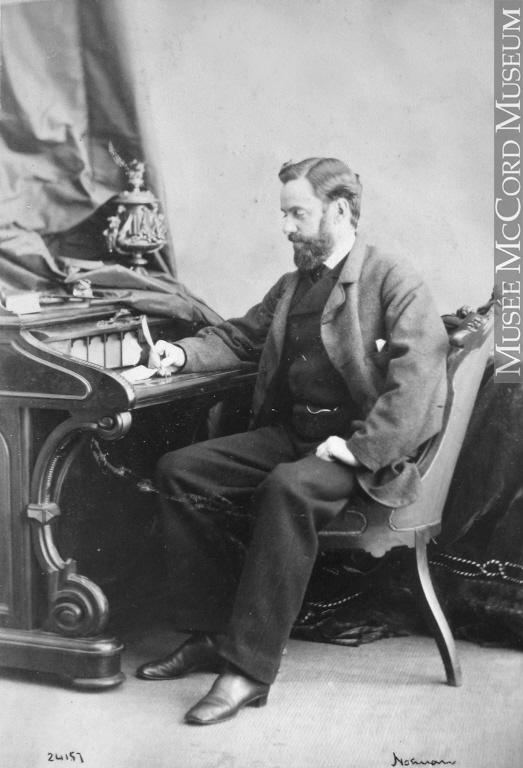 Portrait en pied de Henri-Maurice Perrault, assis de trois quarts sur un fauteuil devant un secrétaire; il tient une plume à la main.