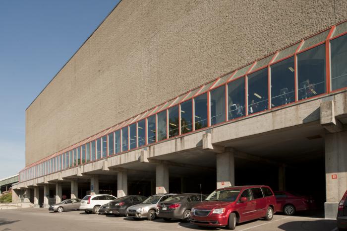 À l’avant, sous le Centre d’éducation physique et des sports de l’Université de Montréal se trouve un stationnement couvert. Photographie.