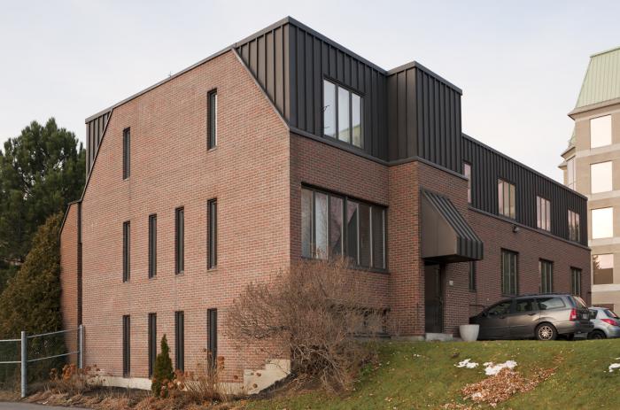 La maison Dujarié est un bâtiment moderne en brique et en aluminium possédant des ouvertures de formes et de dimensions variées. Photographie.