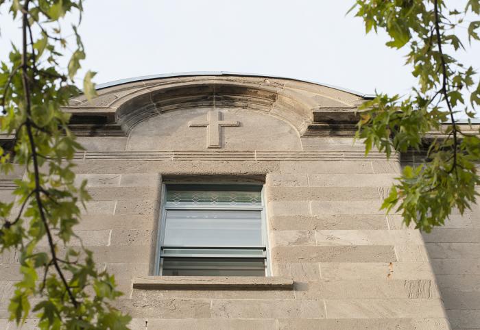 Couronnement cintré du ressaut latéral gauche de la maison Cyrille Laurin dont le traitement en épaisseur renforce la présence de la croix moulurée.